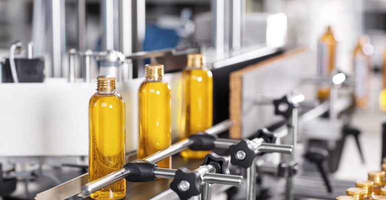 Factory  and research concept. Bottles with yellow thick substance standing on manufacturing facility going to be twisted. Glass bottles in line on conveyor belt. Production process of cosmetics